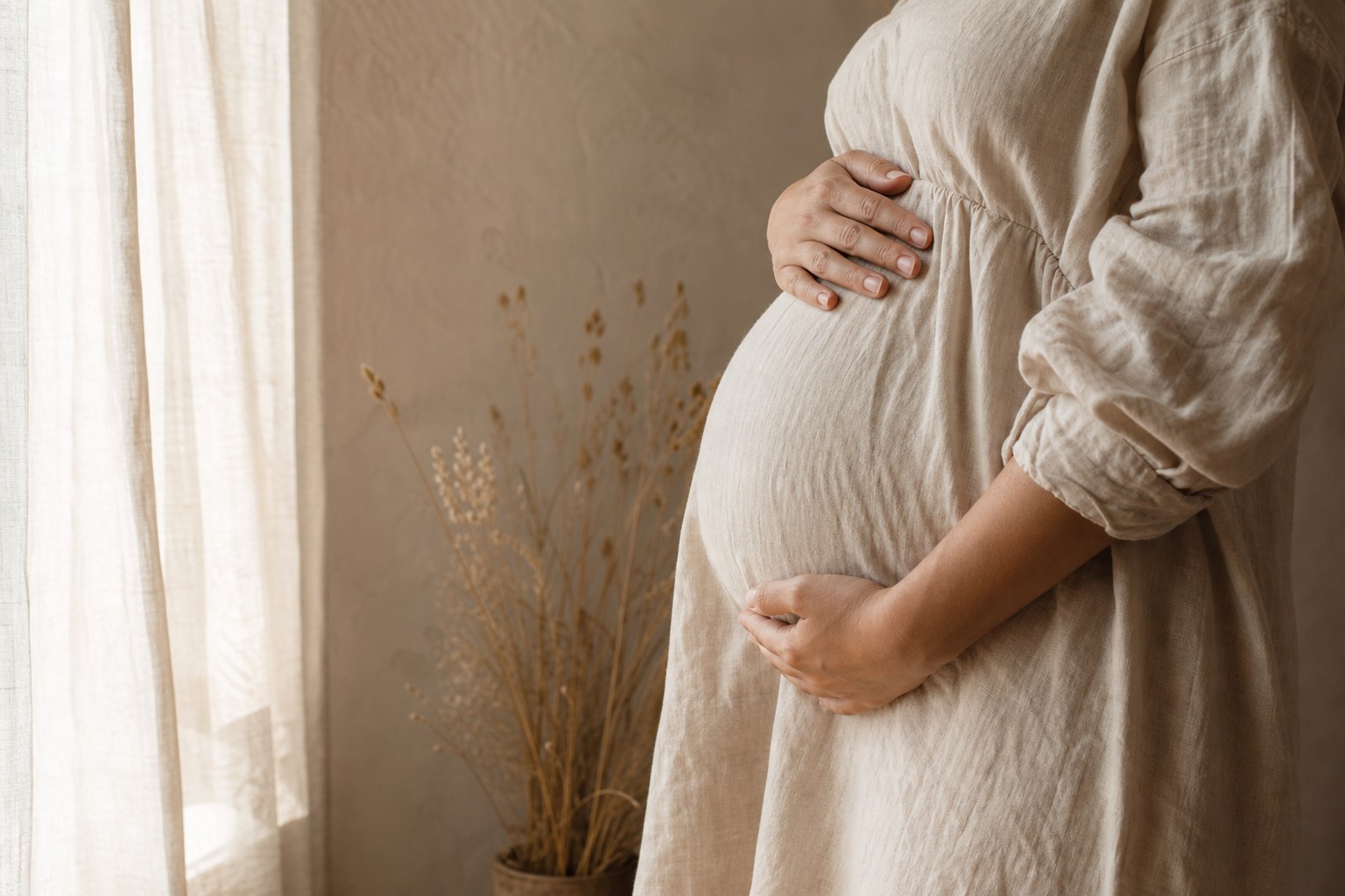 Personne enceinte près d’une fenêtre dans une lumière douce